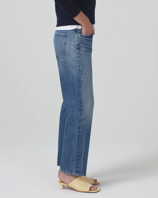 Woman wearing Citizens of Humanity Emery Crop 27" in Oasis denim high rise crop jeans and beige mules.