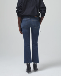 Woman standing with her back to the camera, wearing frayed-hem medium indigo Isola Cropped Boot jeans from Citizens of Humanity.