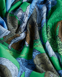 Elegant Inoui Editions Scarf 100 Reverie in Green fabric with an intricate dinosaur print draped in soft folds.