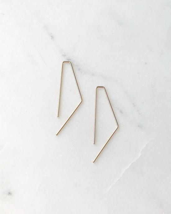 Two Token Jewelry Small Bent Slide Earrings in 14K Gold Fill on a marble surface.