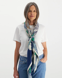 Mature woman posing in a white t-shirt and blue jeans, accessorized with an Inoui Editions Square 130 Robinson scarf in Navy.