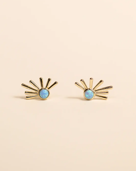 A pair of Sun Ray earrings featuring JaxKelly Fire Opal centers against a beige background.