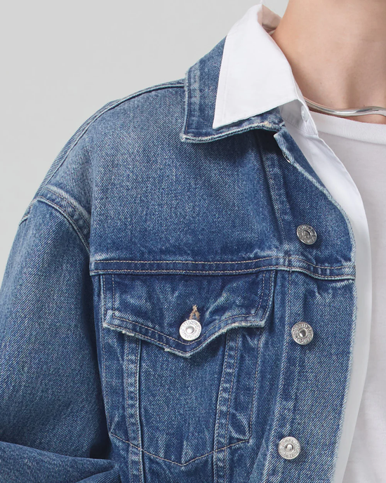 Close-up of a person wearing an Organic Denim Citizens of Humanity Brevity Jacket with a white collar shirt underneath.