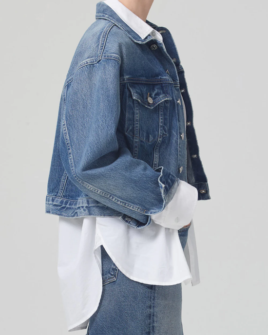 Side view of a person wearing an organic denim Dulce Denim Jacket in Brevity over a white shirt, from Citizens of Humanity.