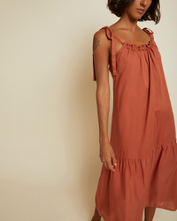 Woman wearing a Nation LTD Sequoia Voluminous Sundress in Tajin cotton voile with tie straps, standing against a neutral background.