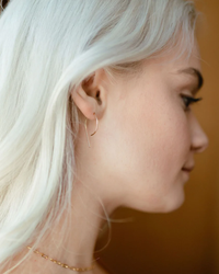 Profile view of a person with platinum blonde hair showcasing Token Jewelry's The Nines Earrings in 14K Gold Fill.
