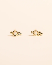 A pair of circular JaxKelly Tri Ball Studs - White Opal earrings with an 18K gold-plated setting on a beige background.