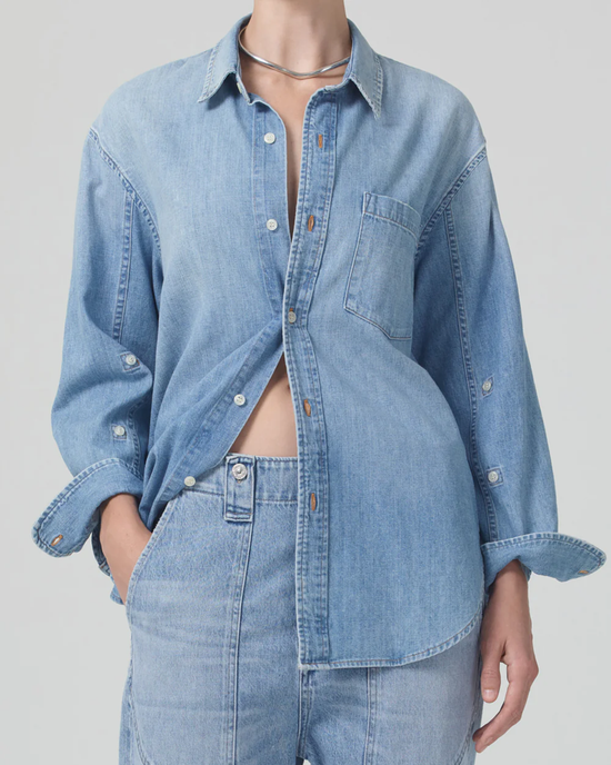 Woman wearing an unbuttoned Citizens of Humanity Kayla Shirt in Tide with an oversized fit and jeans, with a focus on the casual style of the outfit.