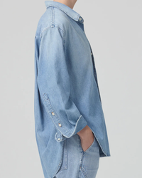Side view of a person wearing an oversized fit, unbuttoned light blue denim Citizens of Humanity Kayla Shirt in Tide.