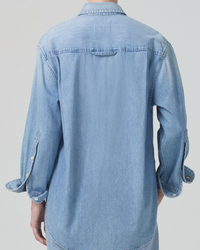 A person standing with their back to the camera, wearing a light blue denim Kayla Shirt in Tide by Citizens of Humanity.