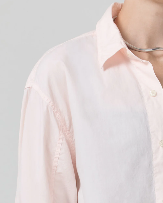 Close-up of a person wearing an oversized fit Kayla Shirt in Guava by Citizens of Humanity with a high low hem, a collar, and a silver necklace.