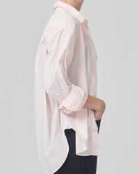 Side view of a person wearing a white oversized fit Kayla Shirt in Guava and black pants from Citizens of Humanity, with one hand in their pocket.
