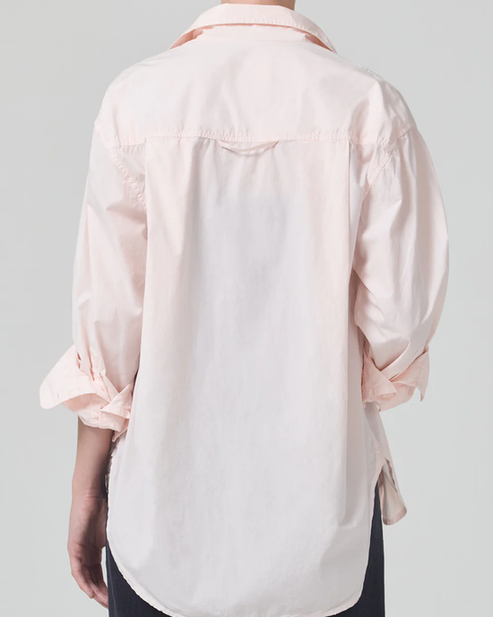 Rear view of a person wearing an Citizens of Humanity Kayla Shirt in Guava with a high-low hem, colored in light pink and white against a neutral background.