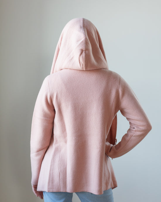 Person standing with their back to the camera wearing a pink cashmere coat from Margaret O'Leary in Adobe and jeans.