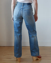 Person standing facing away wearing AMO's Tricia Wide Straight in Joyous blue jeans and clog-style shoes.