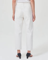 A person from the waist down wearing AGOLDE's white 90s loose fit jeans made from organic cotton and black heeled shoes.