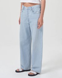 Person wearing AGOLDE Low Slung Baggy in Shake wide-leg blue jeans and black sandals.