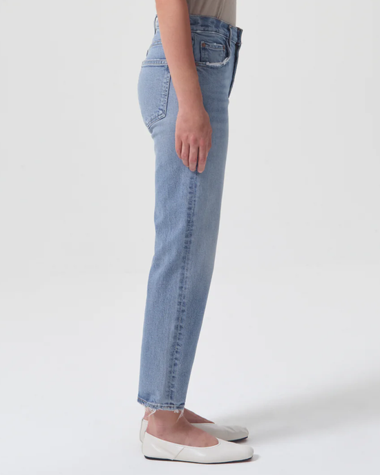Person wearing vintage-inspired, mid-rise straight leg AGOLDE Kye in Foreseen jeans and white flat shoes standing sideways.