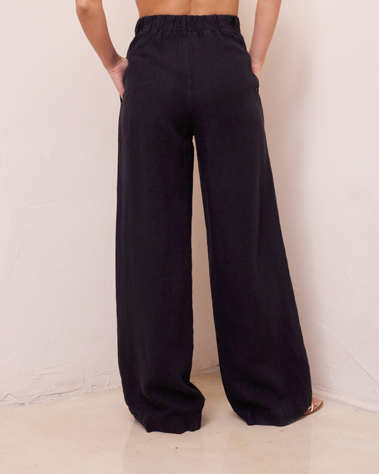 A person standing against a neutral background wearing Bella Dahl's Pleated Wide Leg Trouser in Black.