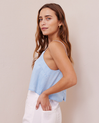 A woman in a Bella Dahl Button Back Cami in Paradis Wash and white bottoms posing with one hand in her pocket.