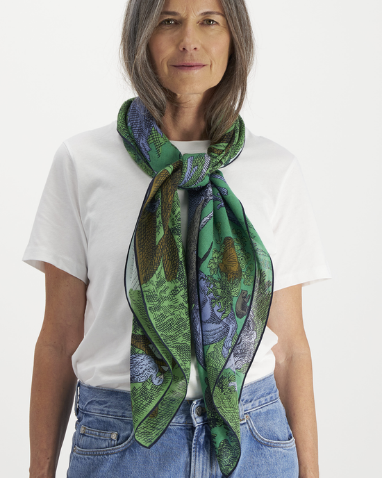 Woman in a white t-shirt and blue jeans wearing an Inoui Editions Square 100 Reverie in Green silk/cashmere scarf.