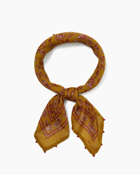 Golden yellow viscose Paisley Bandana in Chai Tea with paisley pattern and tassels, tied in a knot, on a white background by Chan Luu.
