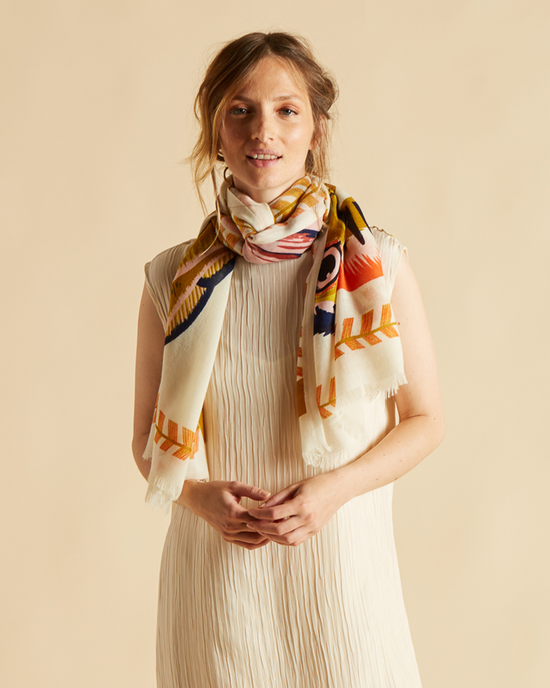 Woman in a pleated dress and an Inoui Editions Scarf 70 Toucan in White smiling at the camera.