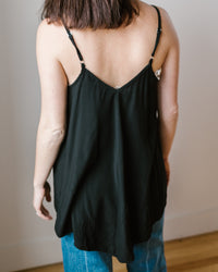 Woman standing with her back facing the camera, wearing a black CP Shades Fairie Tank - Rayon and blue jeans.