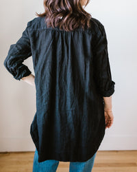 Woman standing with her back to the camera, wearing a CP Shades Teton in Black Heavy Weight Linen Twill tunic and blue jeans.