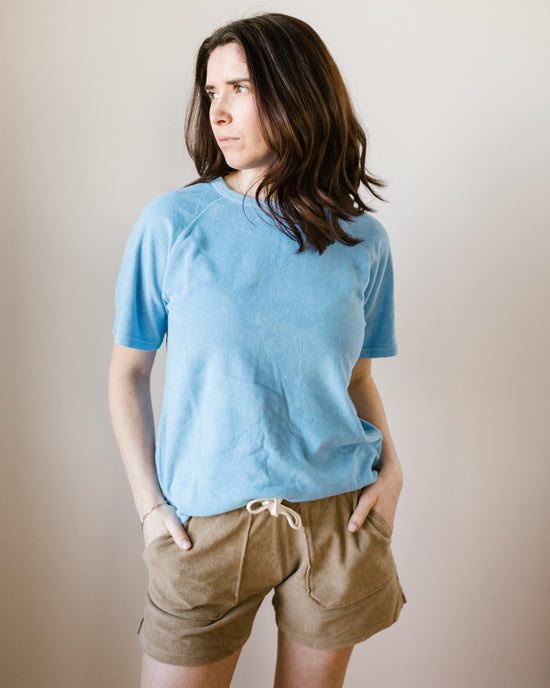 Woman standing in casual Hartford Temery Shirt in Wave and tan shorts against a plain background.