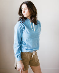 A woman in a Hartford Tarol Hoody in Wave and beige shorts standing against a neutral background.
