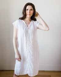 A woman in a 100% Linen CP Shades Lucy Dress w/o Pkts in White HW Linen Twill standing against a neutral background.