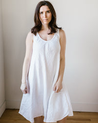 Woman in a CP Shades Bree Dress in White HW Linen Twill standing against a neutral background.