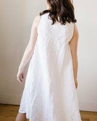 Woman in a CP Shades Bree Dress in White HW Linen Twill standing with her back to the camera.