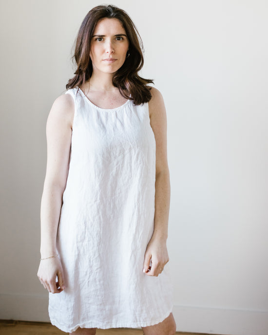 A woman in a CP Shades Jess Dress in White HW Linen Twill standing against a plain background.