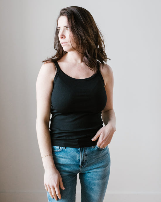 Woman in black Velvet by Graham & Spencer Aliza Tank Top and blue jeans looking to the side against a neutral background.