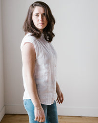 A woman in a Cleo Shirt in White by Hartford with a relaxed silhouette and blue jeans stands against a plain background, looking over her shoulder at the camera.