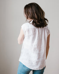 A woman from behind wearing a Hartford Cleo Shirt in White and blue jeans against a neutral background.
