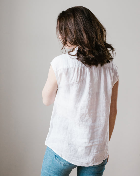 A woman from behind wearing a Hartford Cleo Shirt in White and blue jeans against a neutral background.