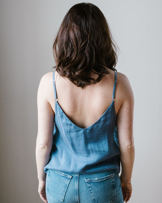 A woman with brown hair wearing a Bella Dahl Mykonos Blue Adj Strap V Neck Cami and jeans, viewed from behind.