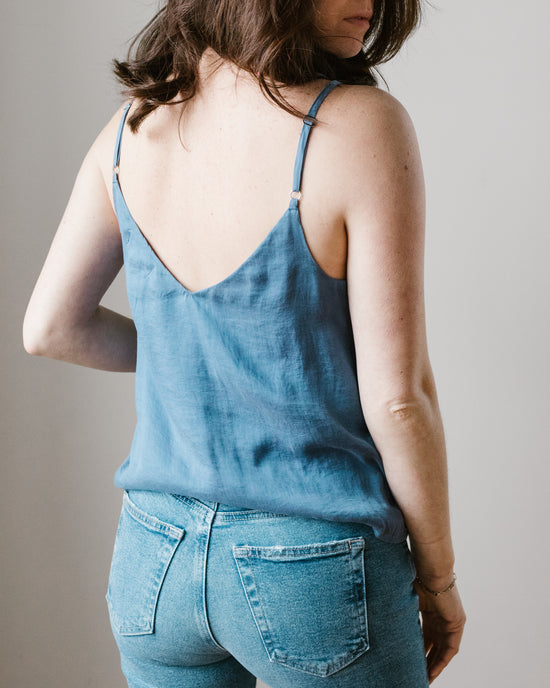 Woman wearing a Bella Dahl Adj Strap V Neck Cami in Mykonos Blue and denim jeans, viewed from behind.