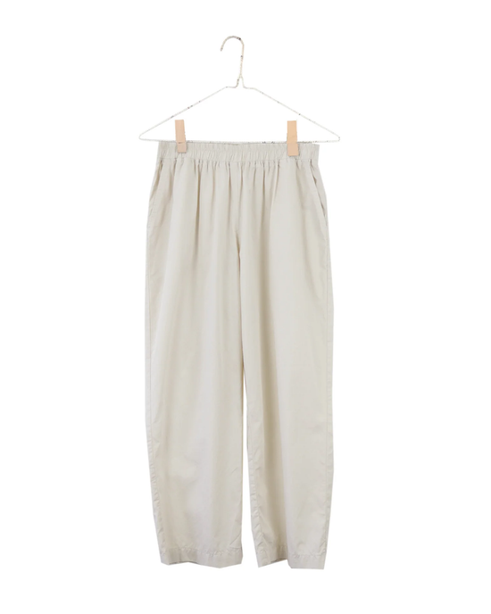 A pair of beige, relaxed fit Everyday Crop Pants in Natural by It is well LA on a hanger against a white background.