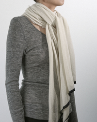A person in a gray long-sleeve top with a Grisal Rosa Cashmere Scarf in Milk X Black, draped around their neck.