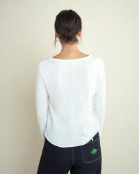 Woman standing with her back to the camera, wearing an American Vintage Sonoma L/S V in Blanc and dark jeans.