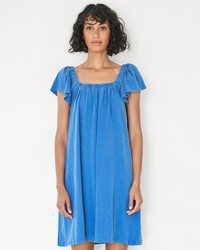 A woman modeling a blue Mini Trapeze Dress in Royal with a ruched square neckline by Sundry.