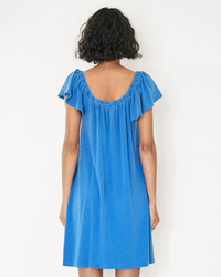 A woman seen from behind wearing a Sundry Mini Trapeze Dress in Royal with mini flutter sleeves and a round neckline.