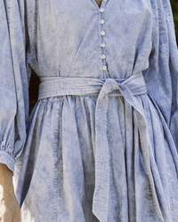 Close-up of The Coast Walk Dress in Hand Dyed Mottled Wash by the Great with a buttoned front and tied waistbelt, featuring voluminous sleeves.