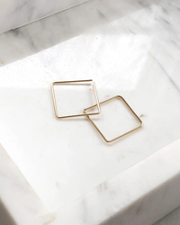 Two Token Jewelry Box Slide Earrings in 14K Gold Fill on a marble surface.