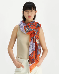 A woman wearing a beige sleeveless top and a decorative multicolored Inoui Editions Scarf 100 Reverie in Terracotta.