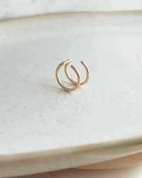 Double Wrap Ear Cuff in 14K Gold Fill from Token Jewelry on a ceramic plate.